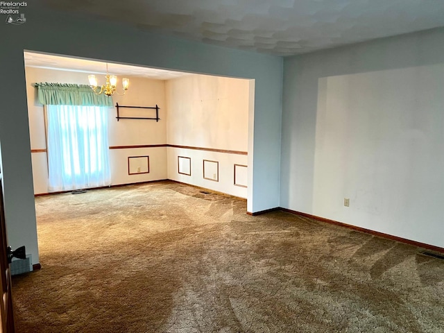 carpeted empty room with a notable chandelier