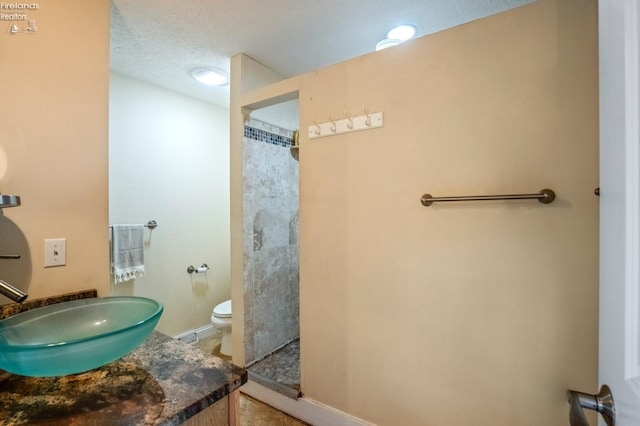 bathroom featuring vanity, a shower, toilet, and a textured ceiling