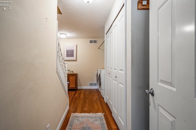 hallway with washer and clothes dryer, a textured ceiling, and wood-type flooring