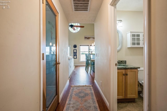 hall with a textured ceiling and dark wood-type flooring