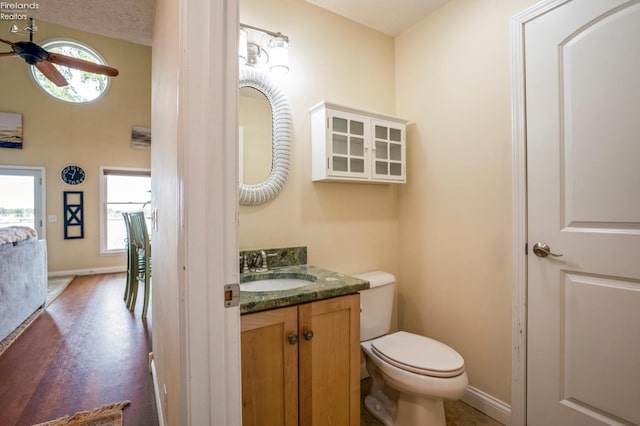 bathroom featuring a textured ceiling, hardwood / wood-style floors, ceiling fan, vanity, and toilet