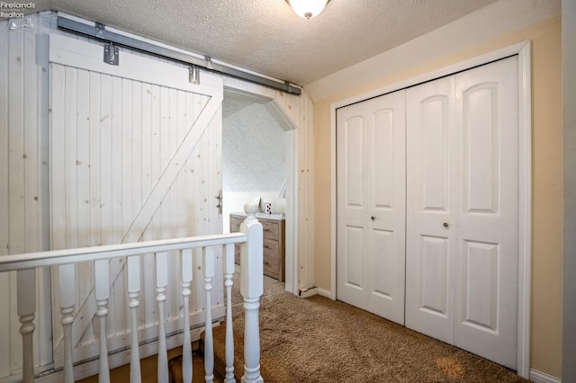 unfurnished bedroom featuring a closet, a crib, carpet flooring, and a textured ceiling