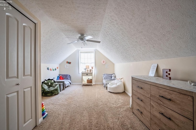 interior space featuring a textured ceiling, carpet, vaulted ceiling, and ceiling fan