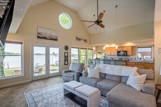 carpeted living room featuring high vaulted ceiling, a water view, ceiling fan, and plenty of natural light