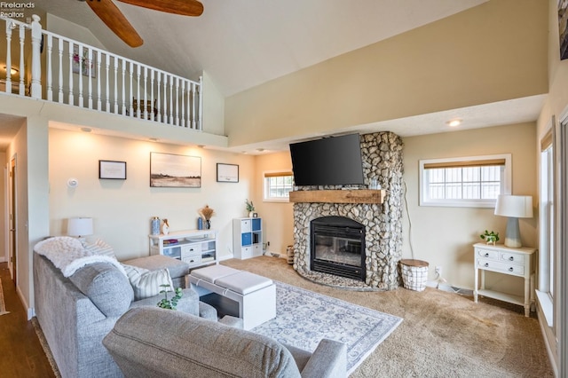 carpeted living room with a fireplace, ceiling fan, and high vaulted ceiling