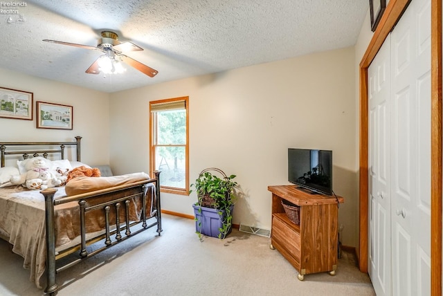 carpeted bedroom with a closet, ceiling fan, and a textured ceiling