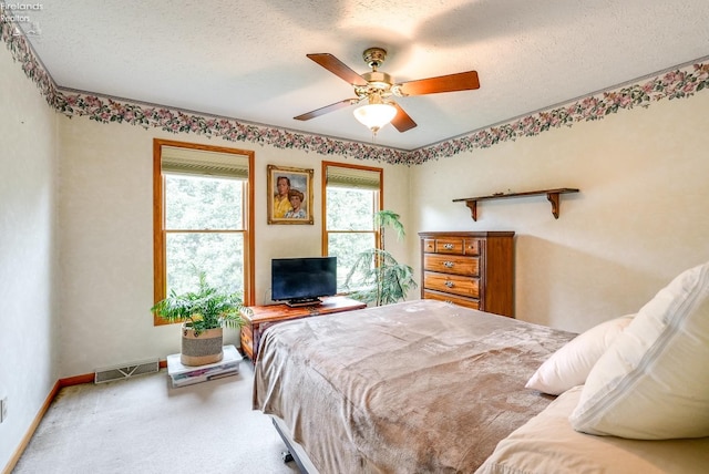 bedroom with ceiling fan, a textured ceiling, and carpet floors