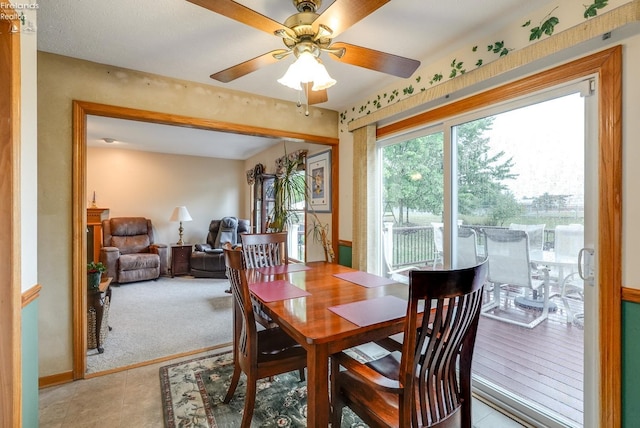 dining space with ceiling fan and light colored carpet