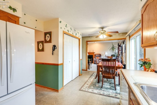 tiled dining space with ceiling fan, a textured ceiling, and sink