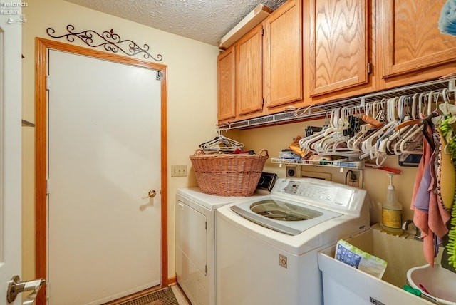 washroom featuring washer and clothes dryer, cabinets, and a textured ceiling