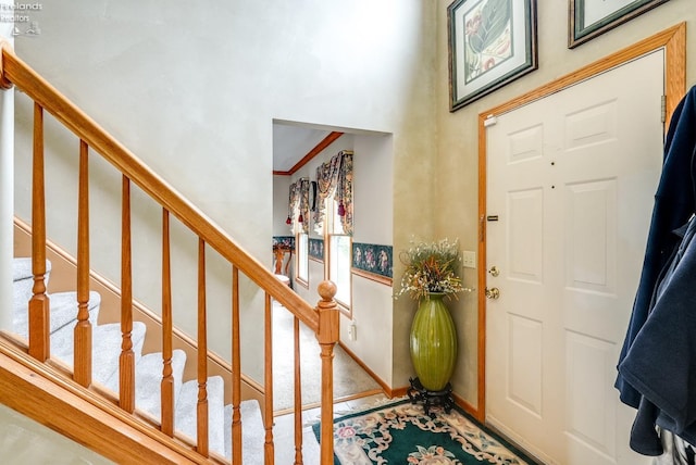 carpeted foyer with ornamental molding