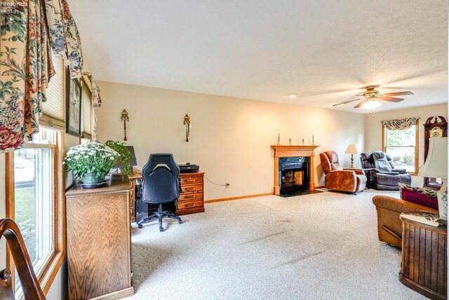 carpeted office space featuring a high end fireplace and ceiling fan