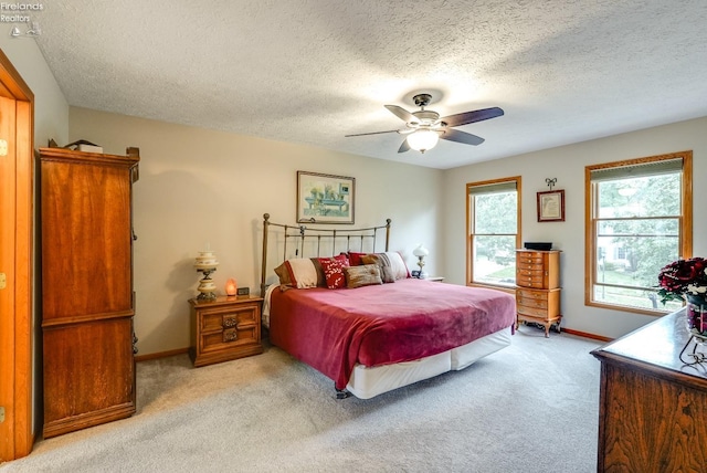 carpeted bedroom with ceiling fan and a textured ceiling