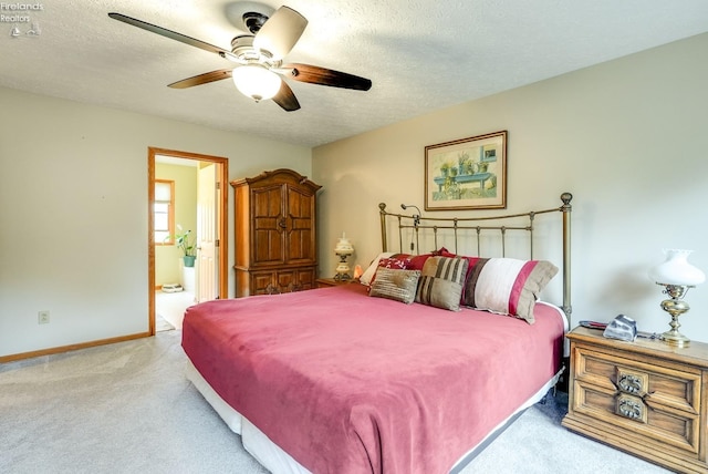 carpeted bedroom with a textured ceiling, ensuite bath, and ceiling fan