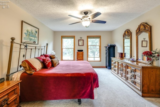 carpeted bedroom with ceiling fan and a textured ceiling