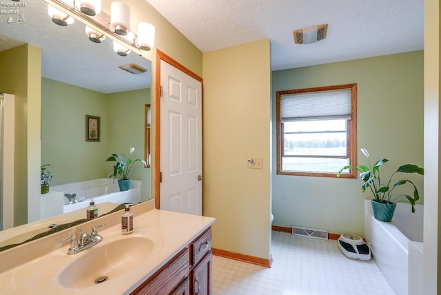 bathroom featuring a textured ceiling, a washtub, and vanity