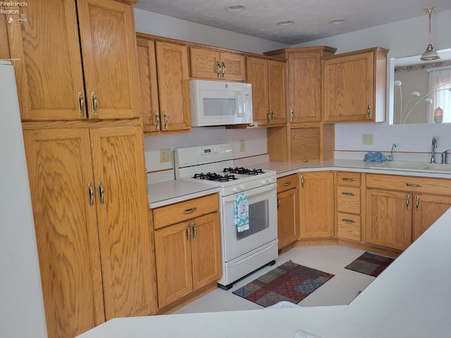 kitchen featuring pendant lighting, a textured ceiling, sink, and white appliances