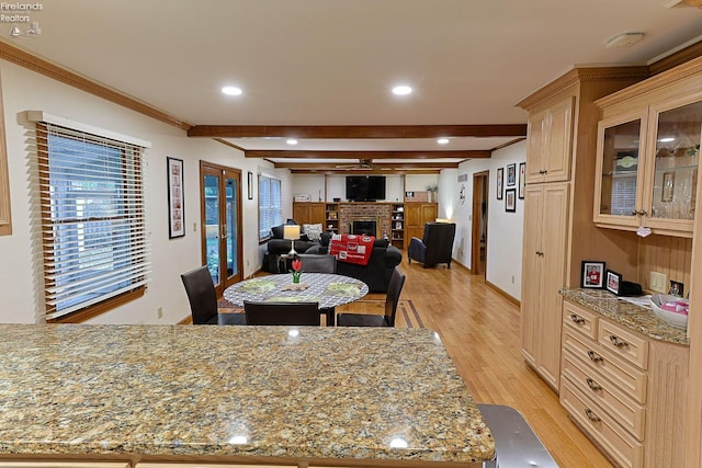 dining space with ornamental molding, beam ceiling, light hardwood / wood-style floors, and a fireplace