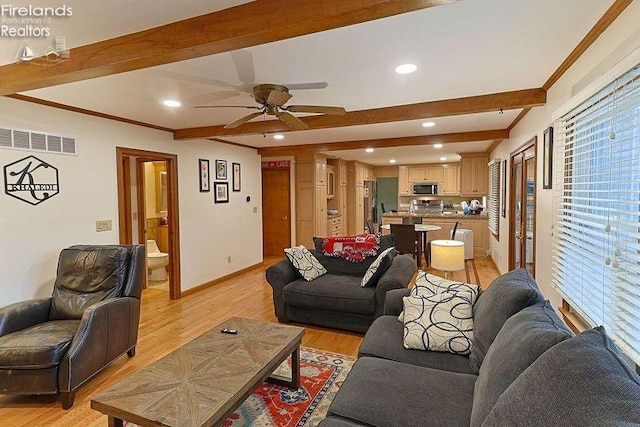 living room with ceiling fan, light hardwood / wood-style flooring, crown molding, and beam ceiling