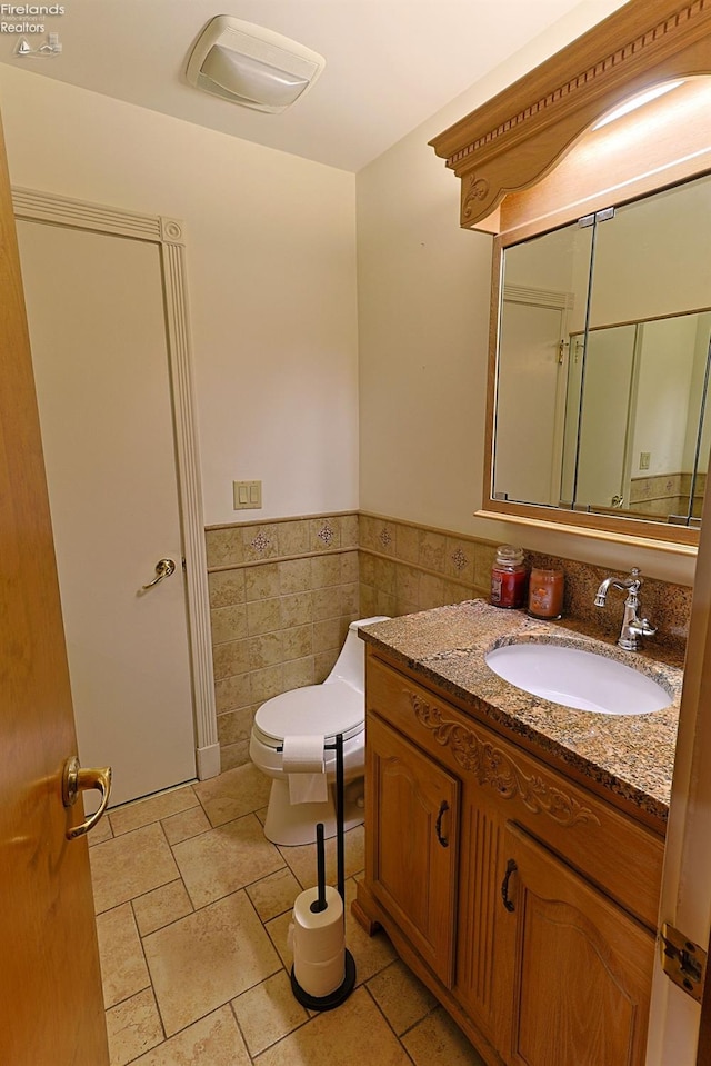 bathroom with tile walls, vanity, and toilet