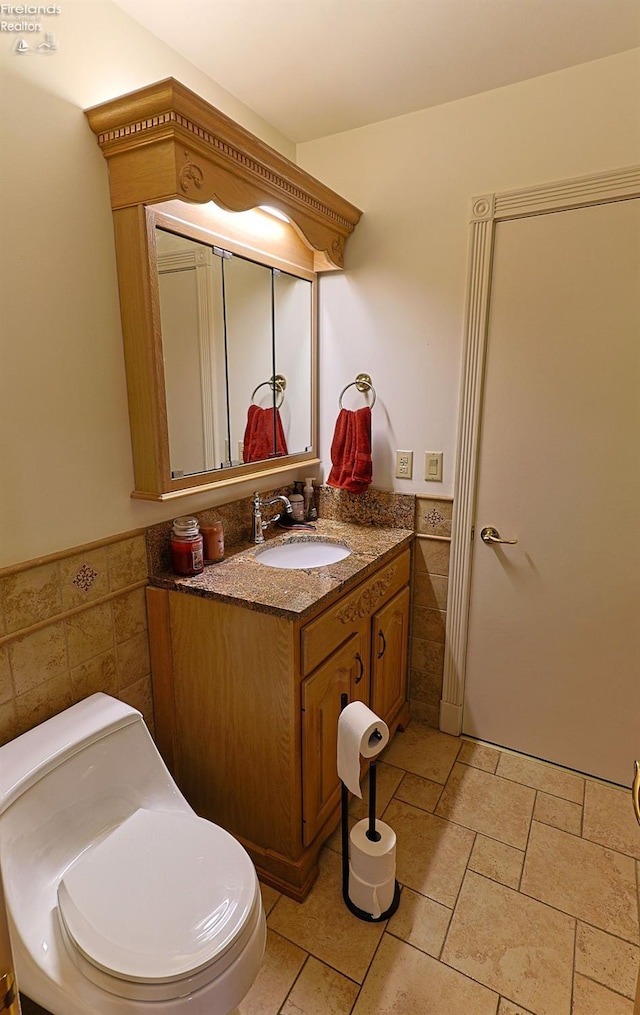 bathroom with tile walls, vanity, and toilet