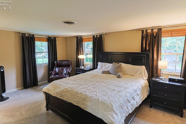 bedroom featuring light carpet and multiple windows