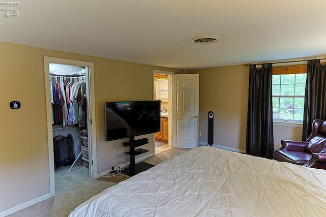 bedroom with a spacious closet, light colored carpet, and a closet