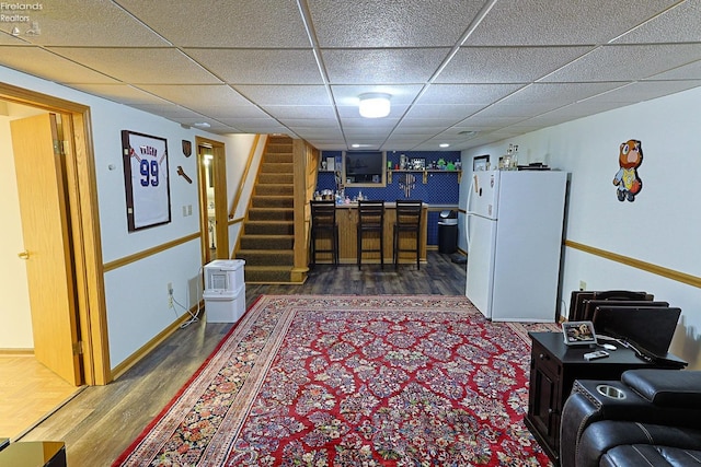 living room with dark hardwood / wood-style floors and a paneled ceiling