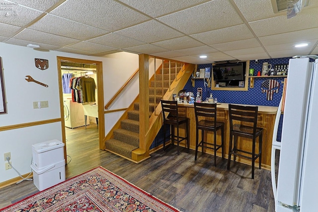 bar featuring a paneled ceiling, washer / dryer, dark wood-type flooring, and white fridge