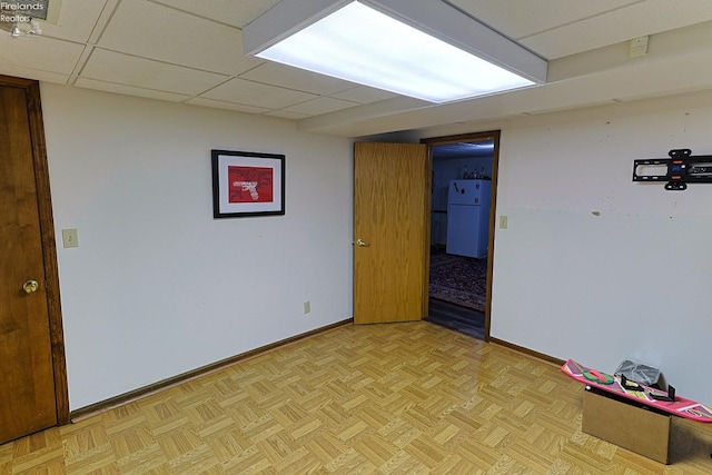 basement featuring white refrigerator, a paneled ceiling, and light parquet floors