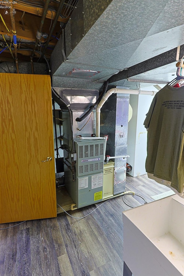 basement with heating unit and dark hardwood / wood-style floors