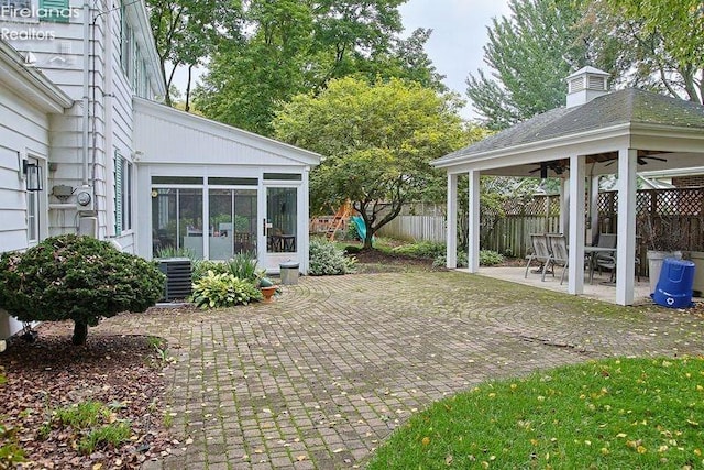 view of patio featuring a sunroom, ceiling fan, and central AC unit