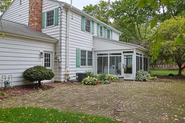 rear view of property featuring a patio area, a sunroom, and central air condition unit