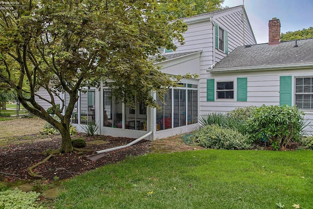 view of side of home featuring a sunroom and a yard