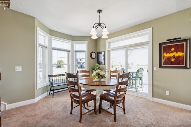 dining space with an inviting chandelier, a textured ceiling, and light colored carpet