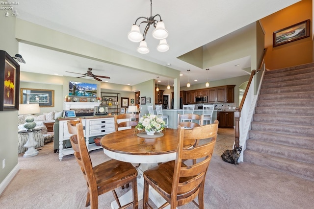 dining area with light colored carpet and ceiling fan with notable chandelier