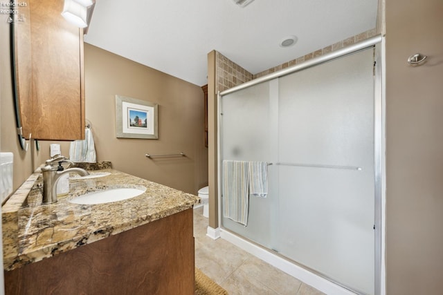 bathroom featuring vanity, tile patterned flooring, toilet, and an enclosed shower