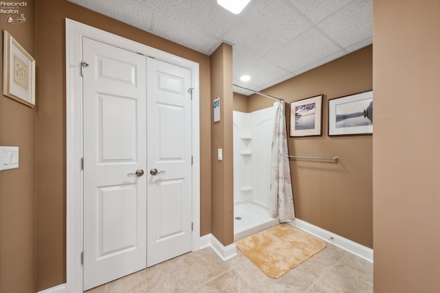 bathroom with walk in shower, a drop ceiling, and tile patterned flooring