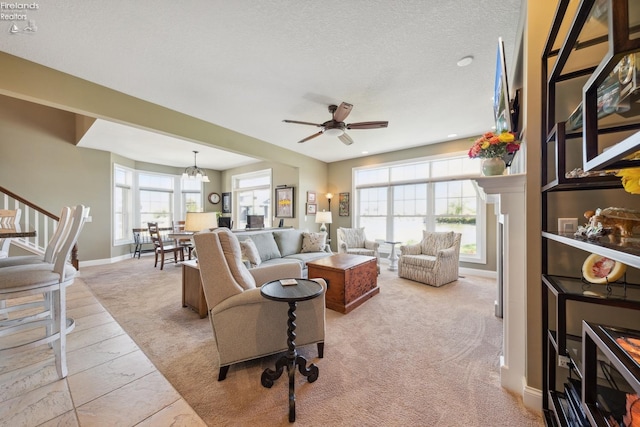 living room featuring light carpet, a textured ceiling, and ceiling fan with notable chandelier