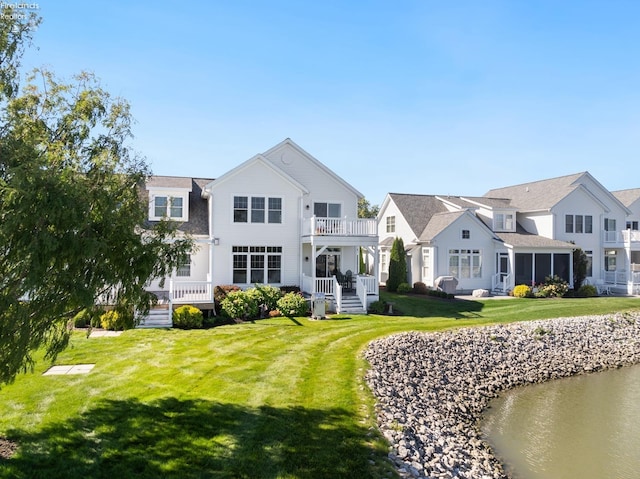 back of house featuring a lawn, a balcony, and a sunroom