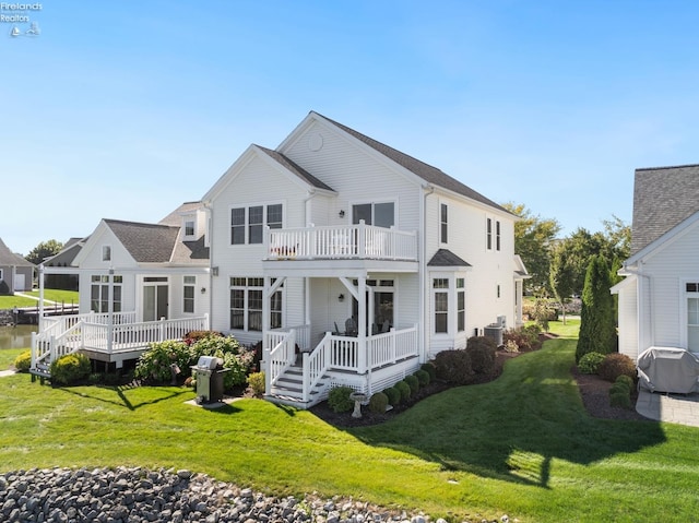 rear view of house featuring a yard, a balcony, and a wooden deck