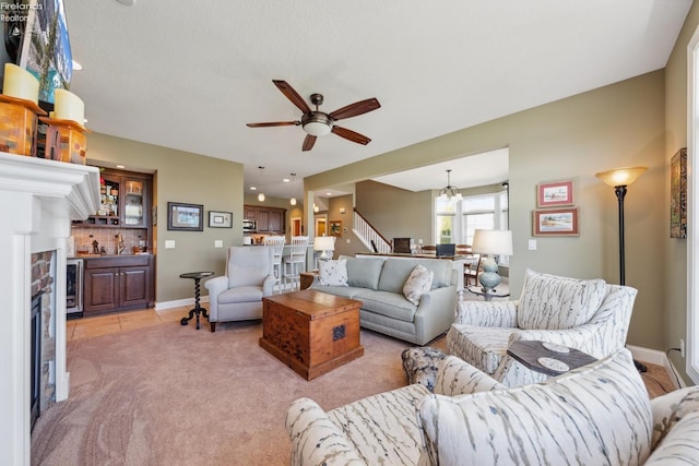 living room with ceiling fan, beverage cooler, a textured ceiling, light carpet, and a fireplace