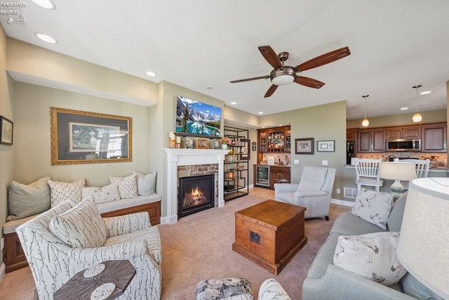 living room featuring a stone fireplace, light carpet, and ceiling fan