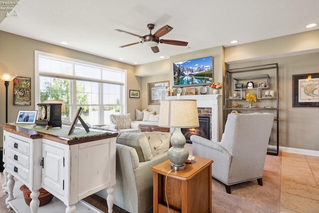 living room featuring light tile patterned floors, ceiling fan, and a brick fireplace