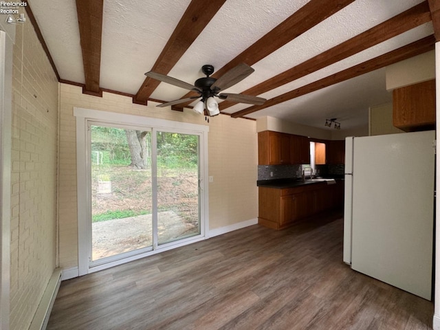 kitchen featuring wood-type flooring, white fridge, beam ceiling, and brick wall