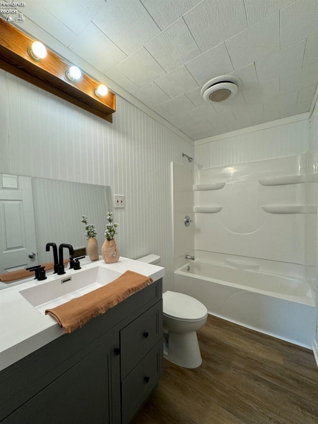 full bathroom with shower / bath combination, vanity, hardwood / wood-style flooring, toilet, and wood walls