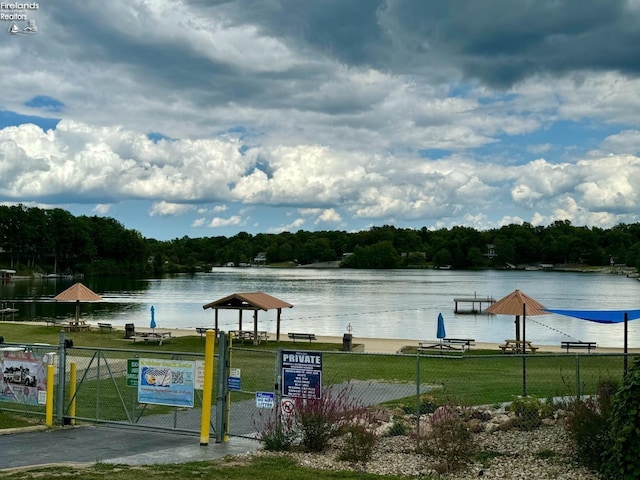 property view of water with a view of trees, fence, and a gate