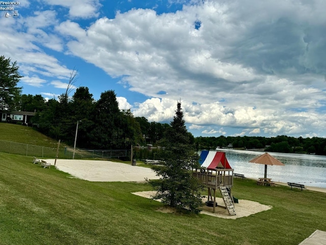 view of community featuring a water view, a lawn, volleyball court, and playground community