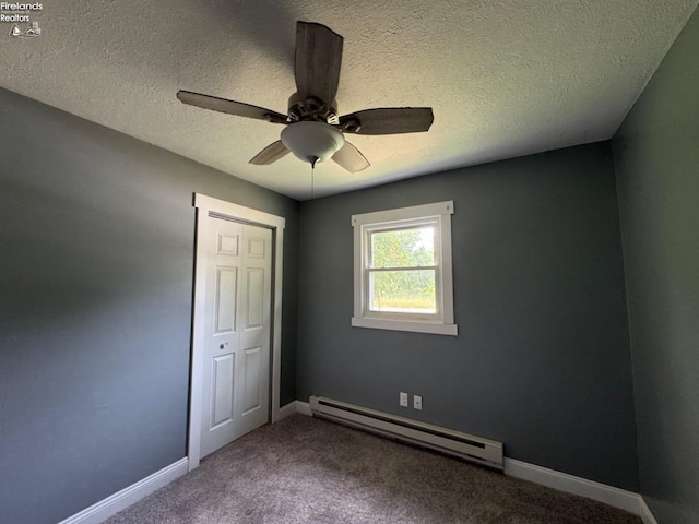 unfurnished bedroom with ceiling fan, a baseboard heating unit, a textured ceiling, a closet, and carpet