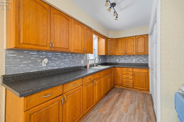 kitchen featuring light wood-style flooring, tasteful backsplash, a sink, and brown cabinetry